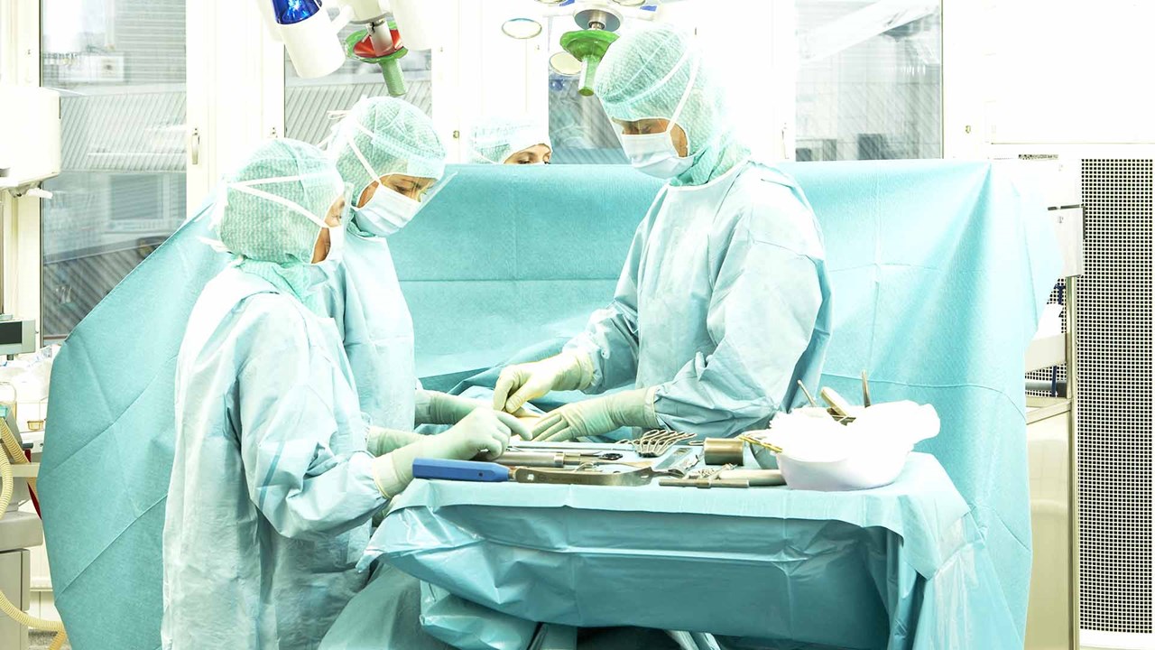 profesionales clínicos en quirófano preparando el instrumental quirúrgico